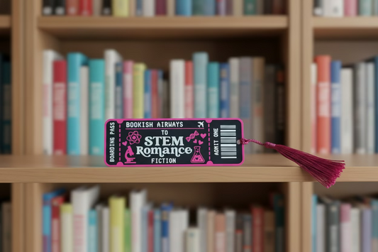 A pink and black novelty bookmark shaped like a boarding pass, printed with the words 'STEM for Romance Fiction' and a purple tassel, shown on a black surface.