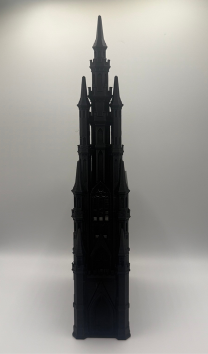 A black gothic-style architectural model or miniature tower with pointed spires, photographed against a plain light gray studio background.