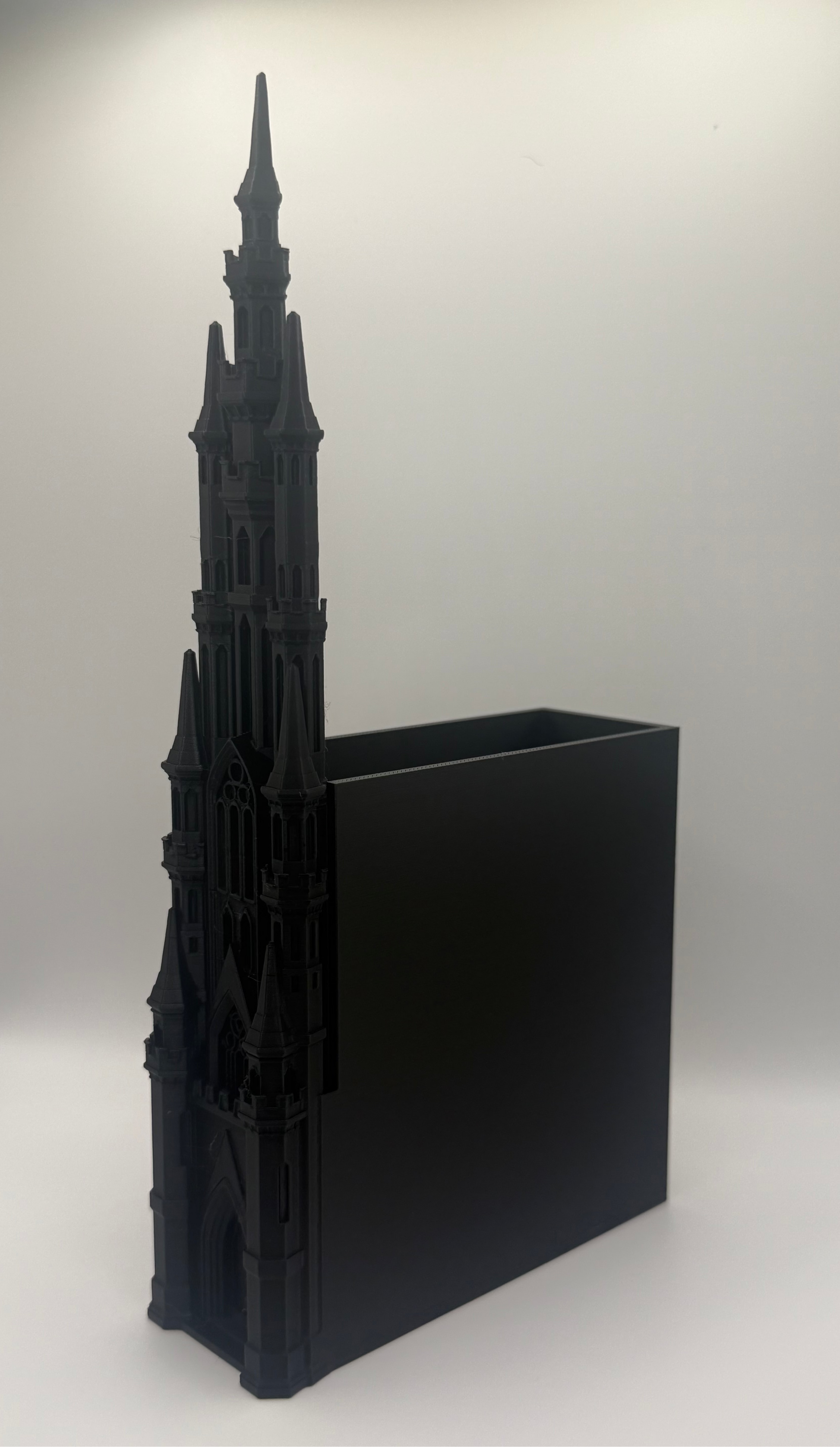 A black gothic cathedral tower desk organizer with a rectangular black insert, photographed on a light gray studio background.